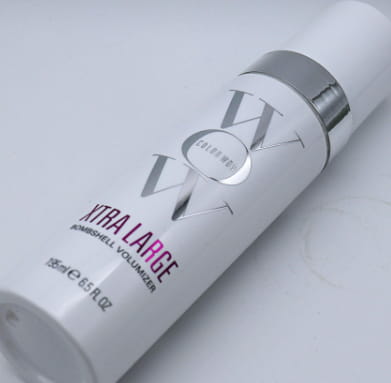 White cylindrical hair volumizer spray bottle with silver metallic cap and Color Wow logo labeled xtra large in pink text for Color Wow Xtra Large Bombshell Volumizer Hair Mousse.