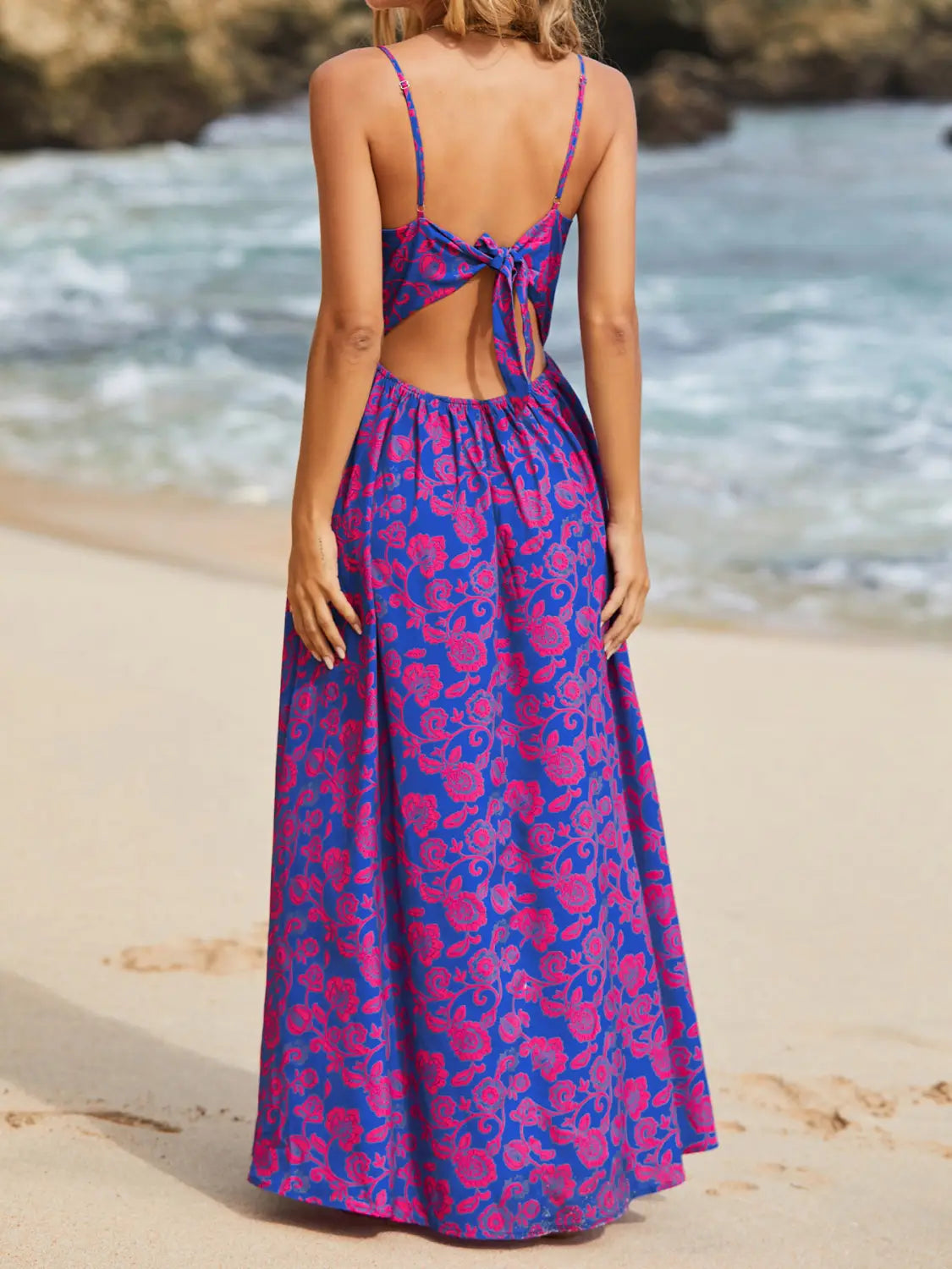 A vibrant blue and pink floral print maxi dress with a v neck, spaghetti straps, and a knotted back tie detail.