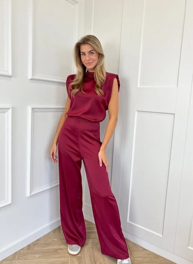 A sleek satin-like burgundy two-piece backless evening dress jumpsuit with a high neckline and wide-leg straight pants.