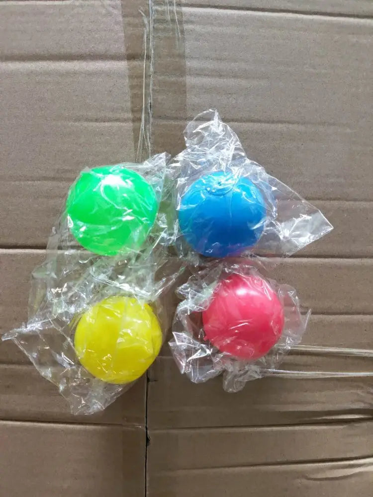 Four brightly colored plastic sticky wall ball stress relief glow squash toys individually wrapped in clear cellophane.