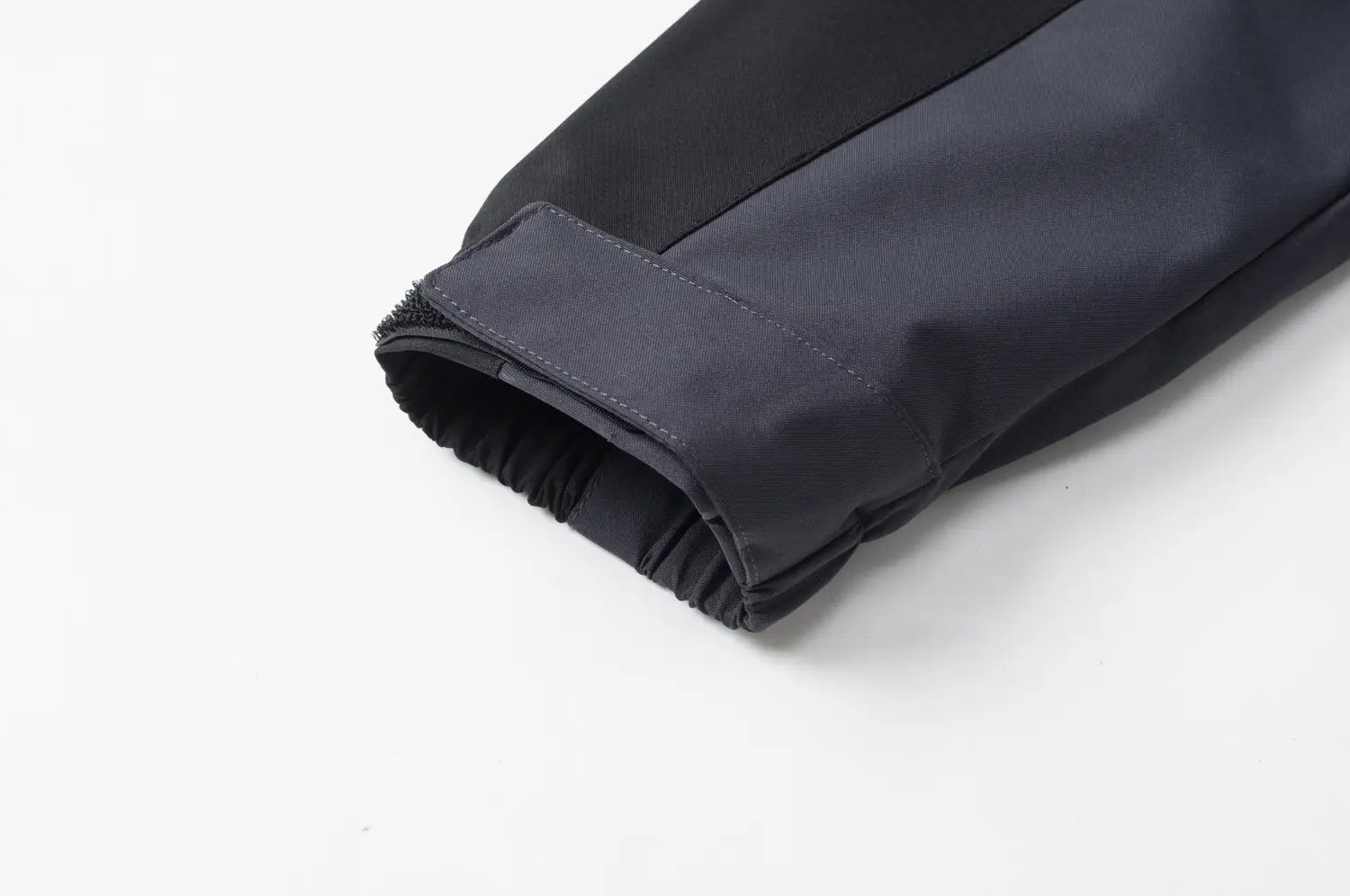 Manche de veste de plein air imperméable à capuche bicolore noire et gris foncé pour hommes et femmes, avec coutures renforcées et poignets élastiqués.