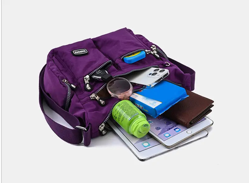 Purple waterproof nylon crossbody shoulder bag with multiple zipped compartments and a black brand patch.