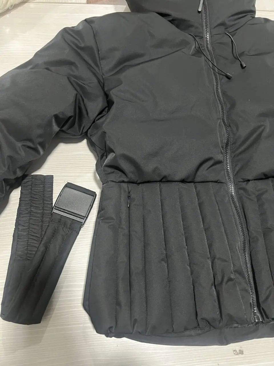Women’s belted hooded black puffer coat with quilted body and ribbed cuffs designed for cold weather.