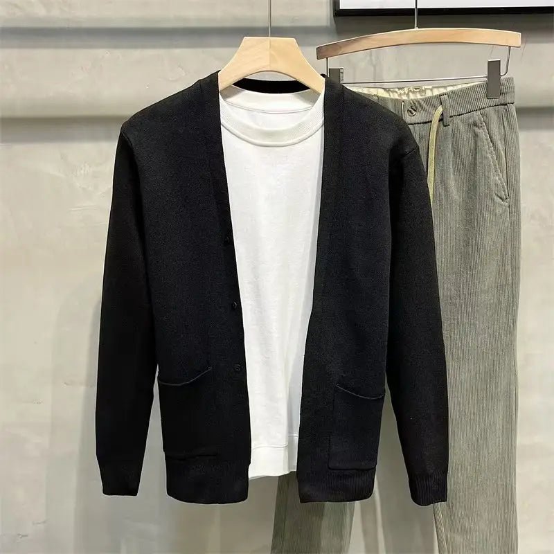 Schwarzer Herren-Strickcardigan mit Knopfleiste und zwei Fronttaschen, getragen über einem weißen Rollkragen.
