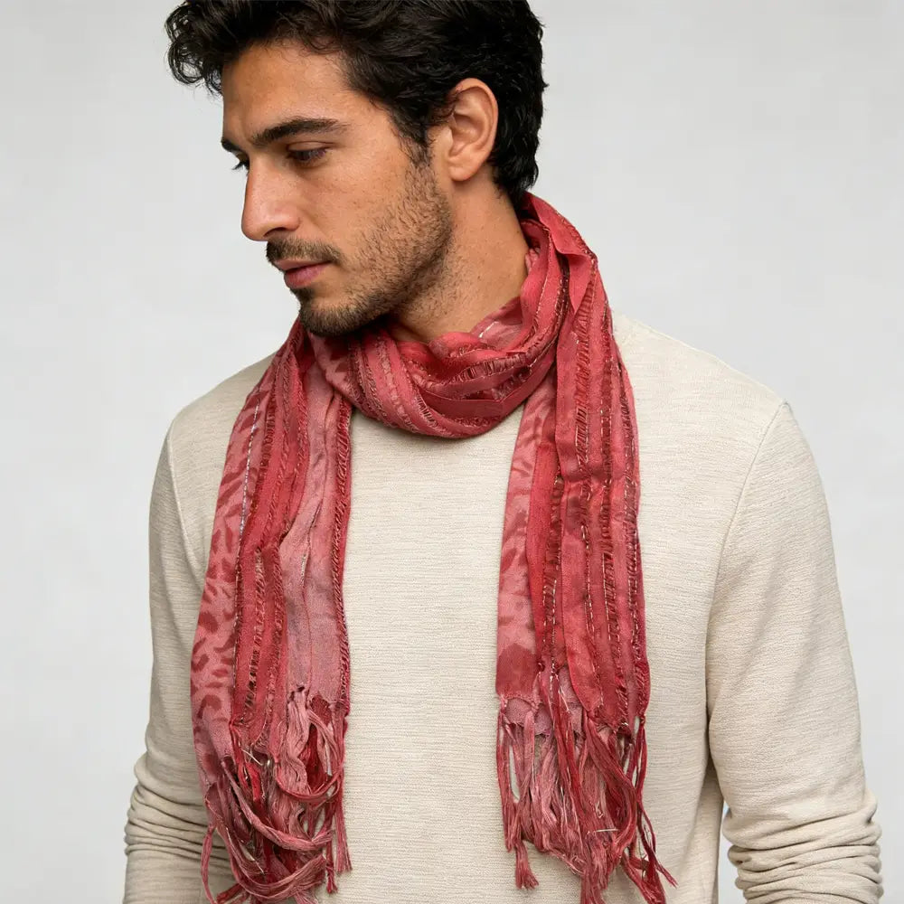 Un foulard en viscose rose poudré tacheté de léopard, doux, de couleur rose poudré, avec des fils métalliques, présentant un motif texturé discret et des bords effilochés.