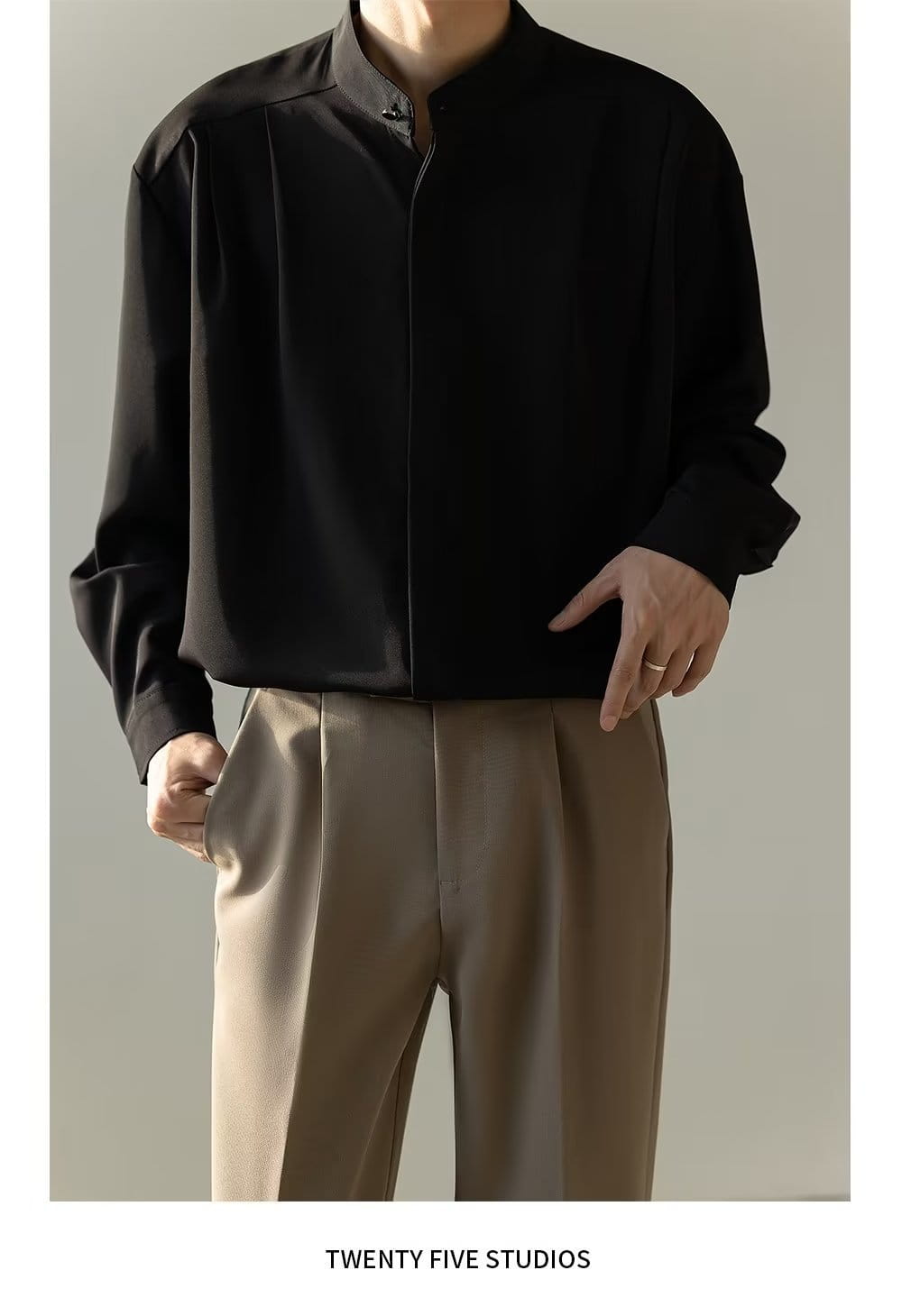 Chemise plissée pour homme à col montant en tissu type satin noir, à manches longues, avec fermeture éclair sur le devant.