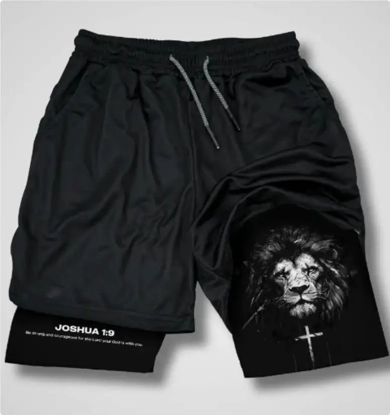 Black faith graphic athletic shorts featuring a detailed black-and-white lion design on the left leg and the text Joshua 1:9 at the hem.