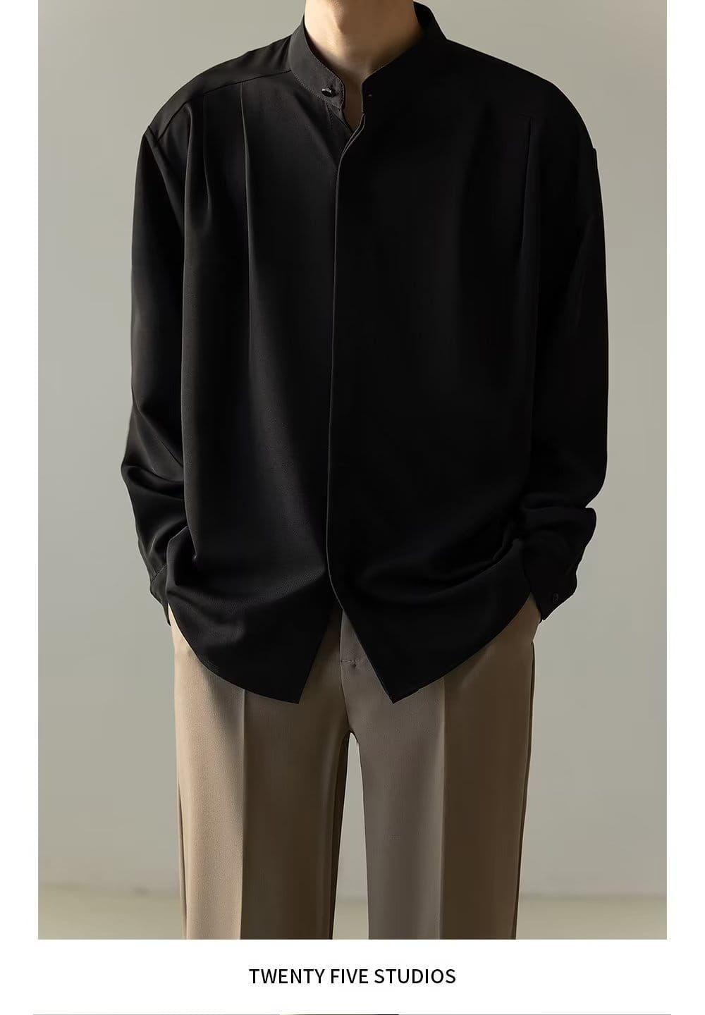 Chemise plissée pour homme à col montant noire, à manches longues, avec des plis avant discrets réalisés dans un tissu souple.