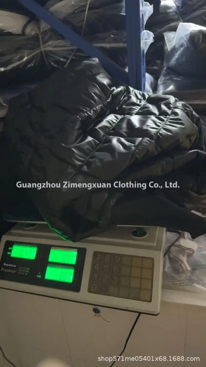 Chaqueta de plumón ligera con capucha acolchada negra, confeccionada con material aislante y colocada sobre una báscula digital.