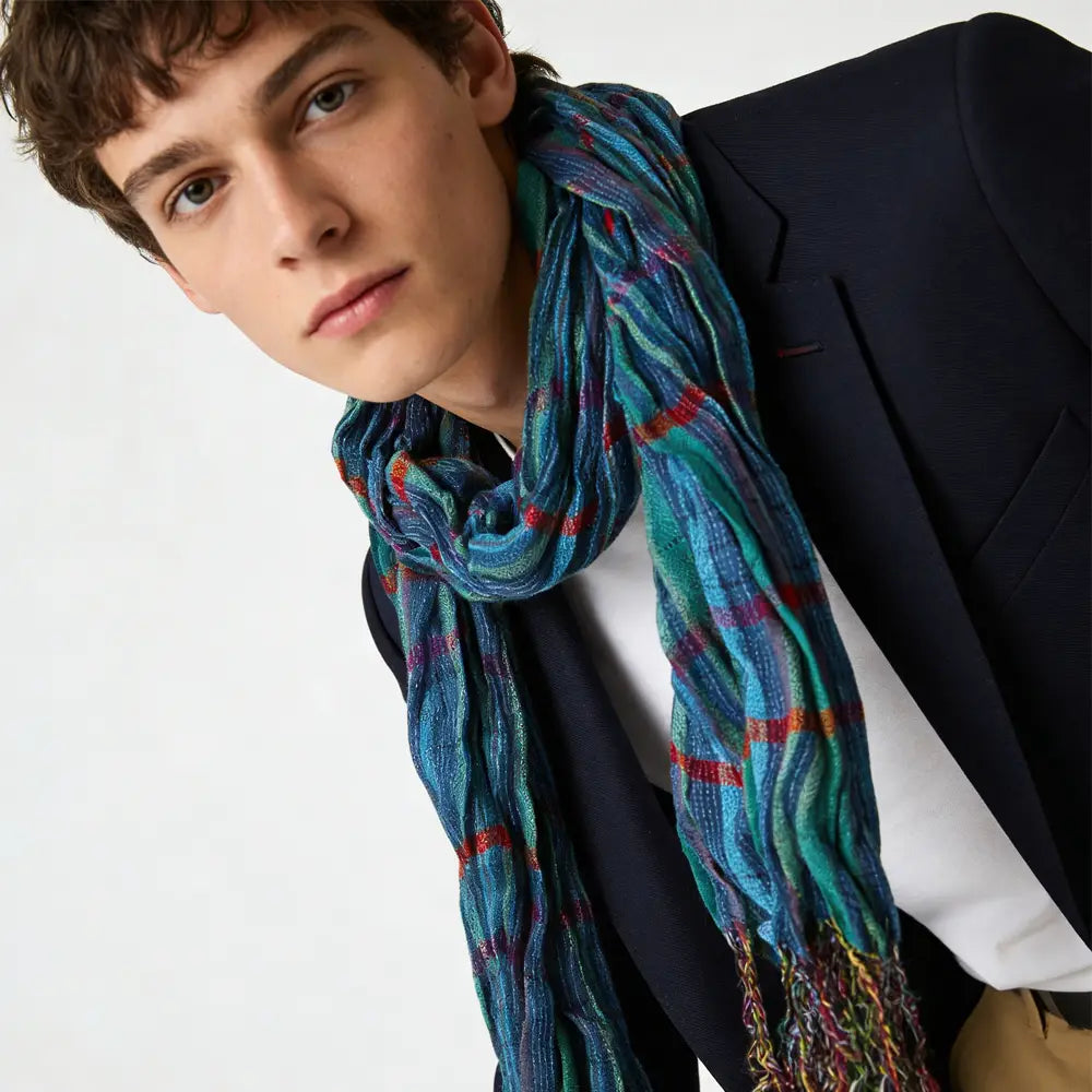 Une écharpe d’hiver bleu à jacquard texturé, présentant des nuances de turquoise et de bleu avec des motifs écossais rouge et violet.