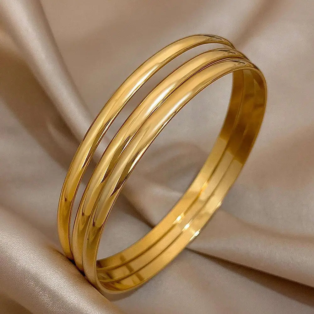 three sleek polished 18k gold plated minimalist stackable bangles stacked together in a set