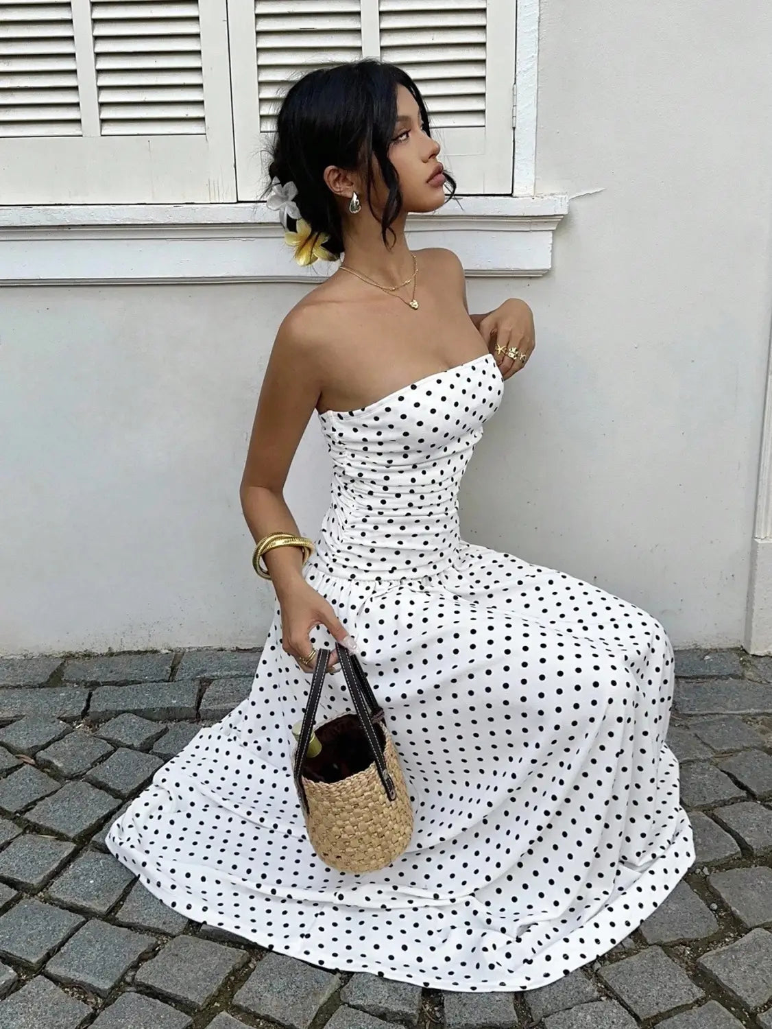 White strapless maxi dress with black polka dots and a ruched bodice suitable for formal occasions.