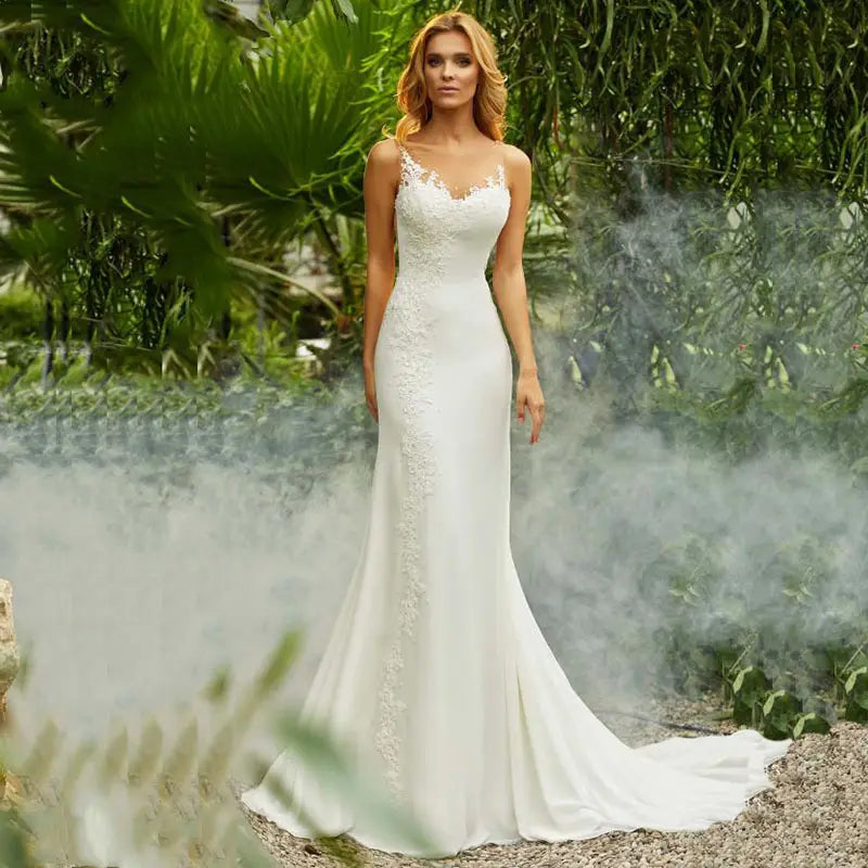 A white lace mermaid wedding dress with a fitted silhouette, delicate floral embroidery along the bodice and side seam, and a train.