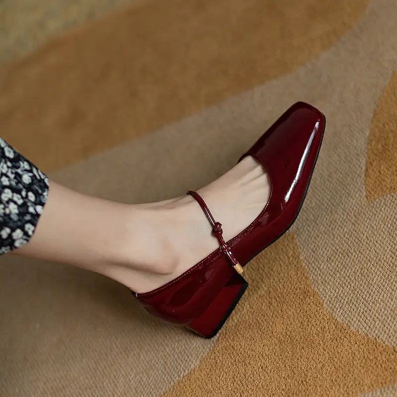 Burgundy patent leather square toe mary jane flats with ankle strap and block heels.