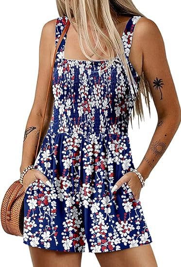 Mono de estampado floral azul sin mangas con flores blancas y rojas, escote cuadrado y cintura elástica, adecuado para vestir en la playa durante el verano.