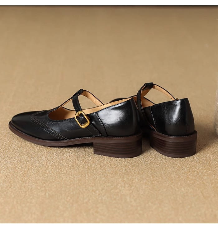 Schwarze Leder-Mary-Jane-Pumps mit klobigem Absatz mit goldfarbenem Schnallenverschluss und Brogue-Verzierung.