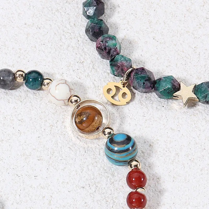 A colorful natural stone zodiac constellation beaded bracelet featuring faceted green and purple gemstones, a gold-toned zodiac charm, a star pendant, and assorted round beads in red, blue, turquoise, white, and brown.