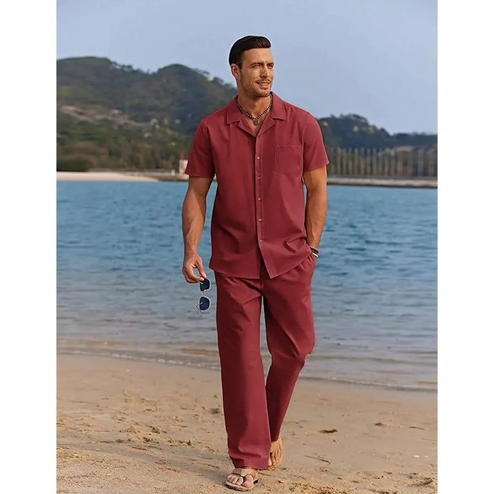 A man wearing a matching maroon short sleeve shirt and trousers set paired with sandals.