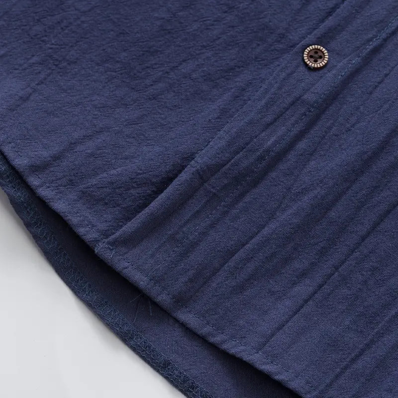 Men’s linen blend sleeveless hooded button up shirt in deep blue textured cotton with a subtle ribbed pattern and dark brown button.