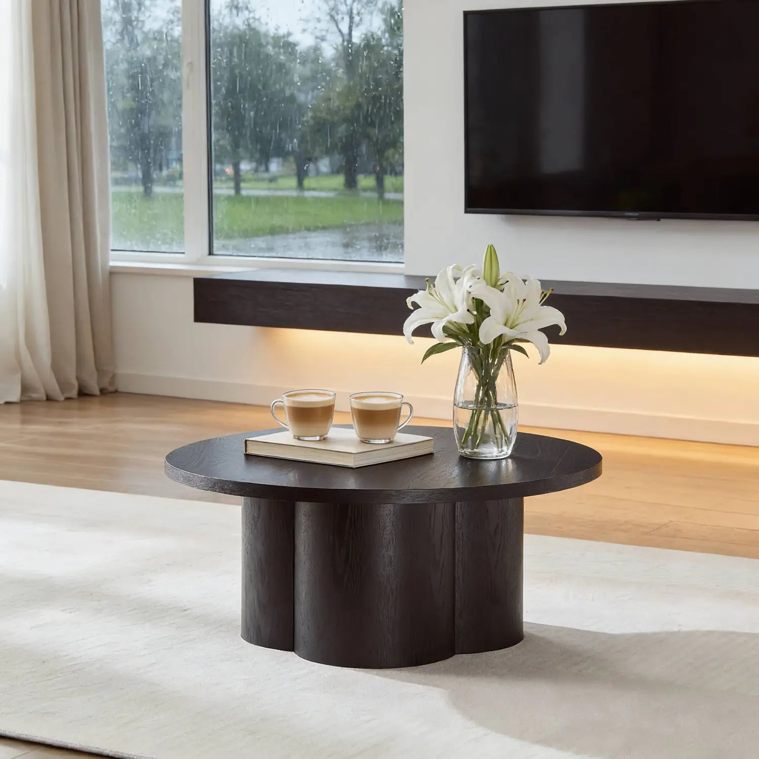 Mesa de centro redonda de madera oscura con una base esculpida moderna y una tapa circular lisa diseñada como pieza de acento.