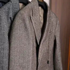 A gray herringbone wool slim tweed blazer with a classic double-breasted design and dark buttons, featured as a British vintage woolen coat.