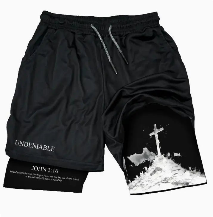faith graphic athletic shorts in black feature a white cross and biblical text printed on the side with an elastic waistband and gray drawstrings.