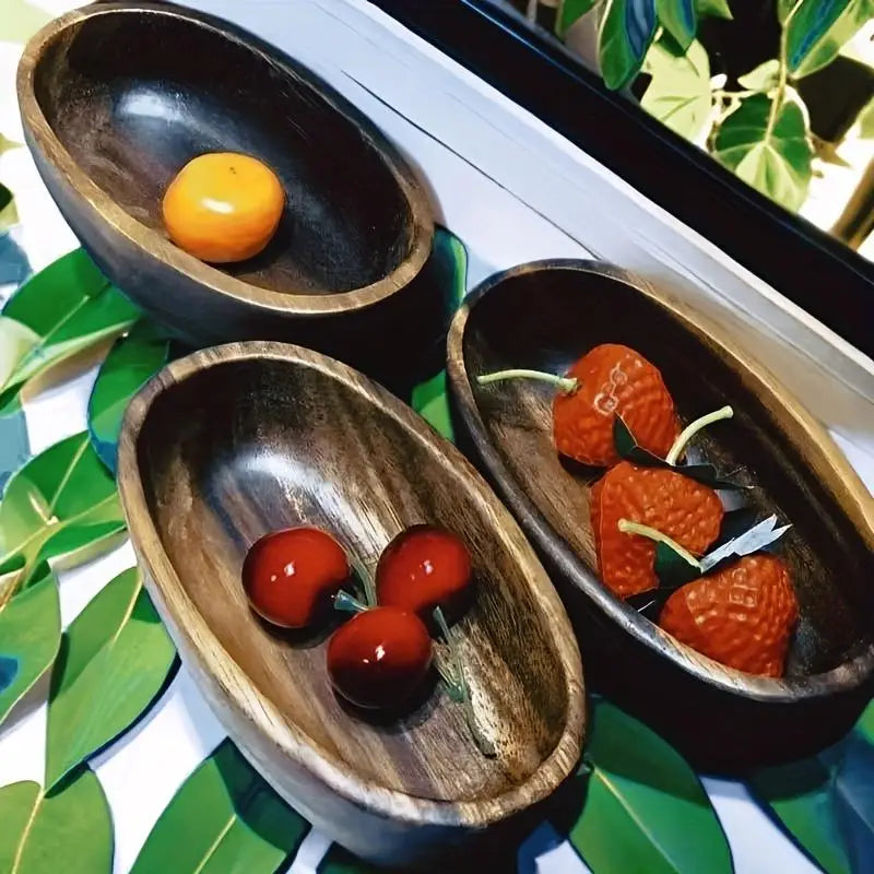 Tres cuencos de sushi de madera artesanal con forma ovalada, con interiores de color marrón oscuro y exteriores de vetas de madera natural, que contienen pequeñas decoraciones de frutas en un set de barco de madera para sushi japonés.