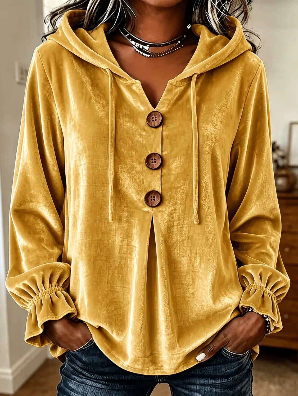 Sudadera de terciopelo color mostaza con botones de madera y puños fruncidos, exhibida de frente.