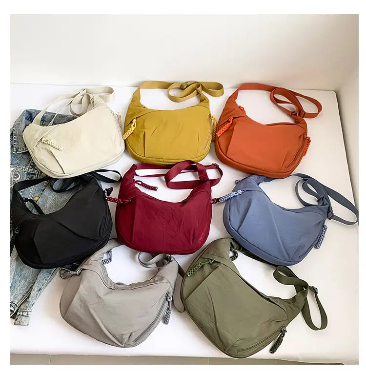 A collection of seven colorful nylon crossbody bags featuring large capacity and lightweight hobo shoulder designs in cream, mustard yellow, orange, black, red, blue, and olive green.