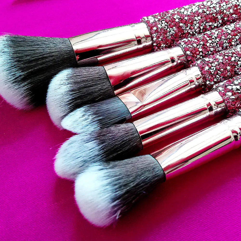 Set of five rhinestone makeup brushes with sparkling pink and silver rhinestone handles, rose gold ferrules, and soft black and white bristles from the rhinestone makeup brush set with bag 10 piece pink.