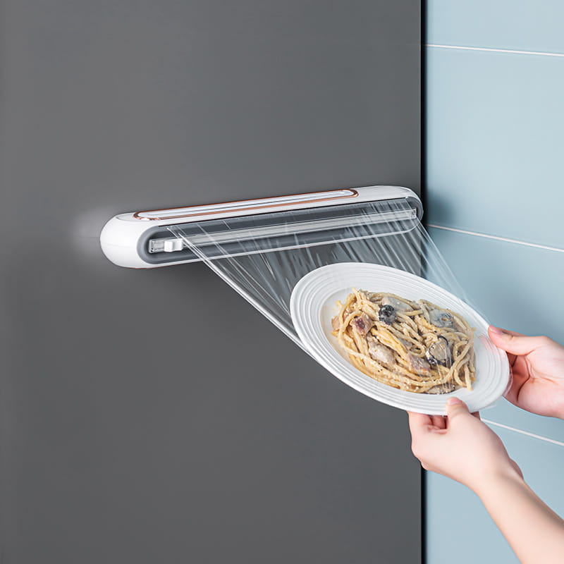 White wall-mounted magnetic cling film cutter and plastic wrap dispenser with sleek modern design and rose gold accents.