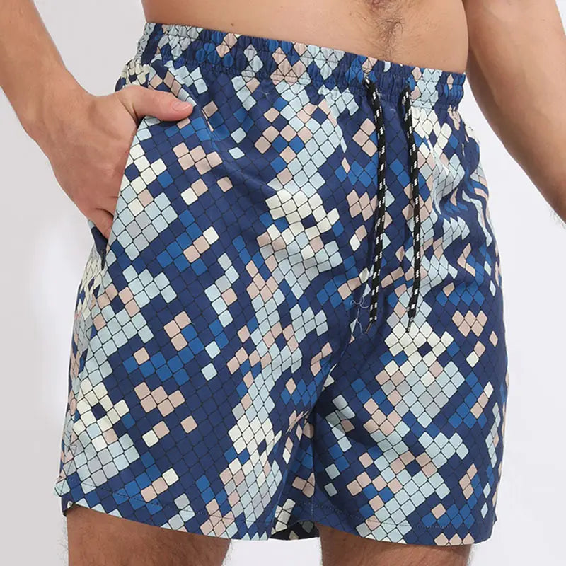 Men printed swim trunks sports beach shorts featuring a blue and beige pixelated pattern with a drawstring waistband.