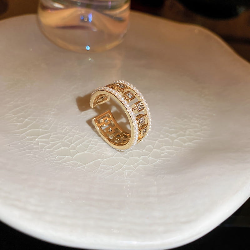 Gold-toned open ring featuring a hollowed square geometric pattern with clear pearl and baguette zircon crystals embedded along its edges.