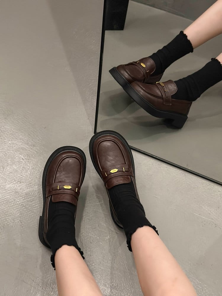 Brown leather loafers with a matte finish and gold-tone metal buckle detail on the front strap.