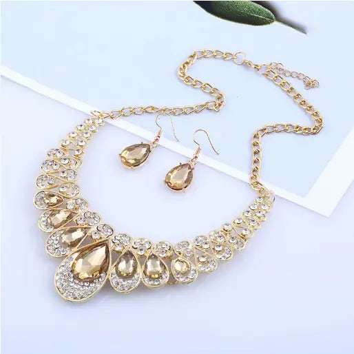 Vintage gold teardrop crystal bridal jewelry set featuring a gold-toned necklace with teardrop-shaped amber-colored stones and smaller clear crystals in a decorative layered design.
