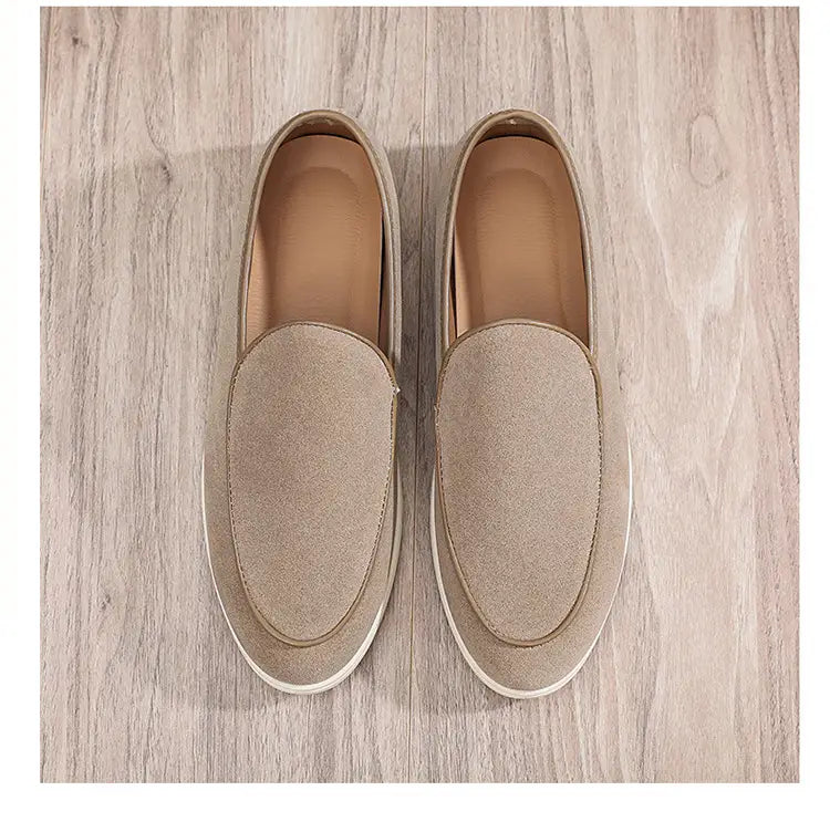 Beige suede men’s slip-on loafers with a white rubber sole shown from the back side.