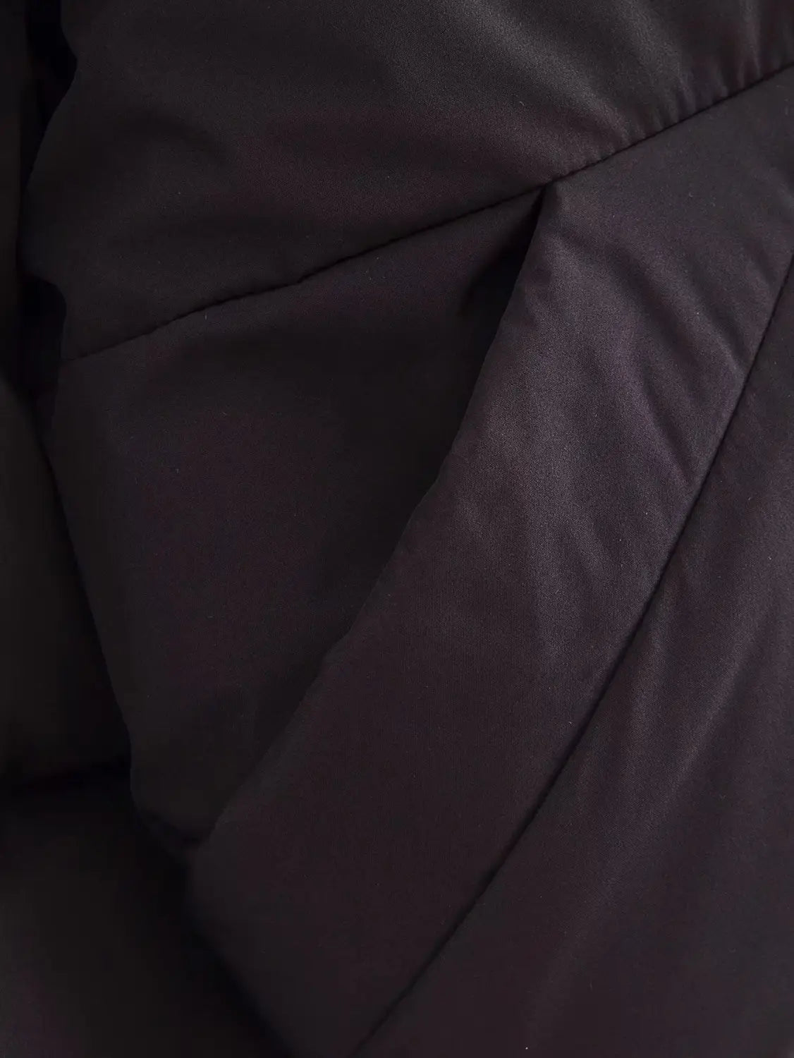 Black quilted hooded puffer coat featuring stitched panels and smooth slightly reflective fabric in black.