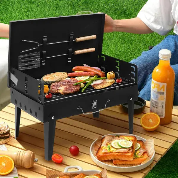Black portable charcoal grill 44cm folding square bbq made of steel with built-in tools and a handle for easy transport.