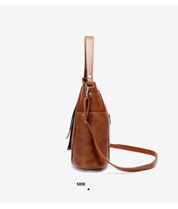 Leather hobo bag in brown leather featuring a detachable strap black tassel detail and front zipper pockets.