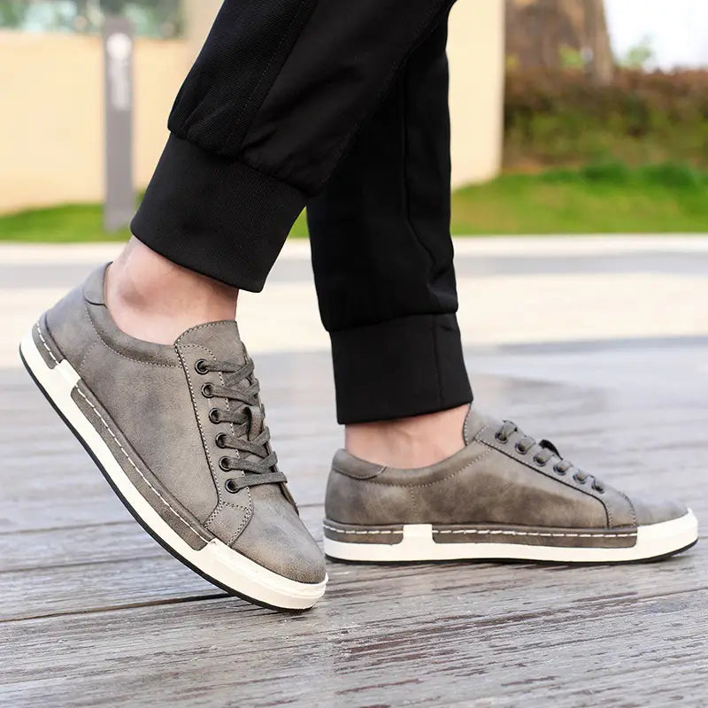Les baskets basses en cuir pour homme, faites à la main, en daim gris, avec des semelles en caoutchouc blanc et des coutures contrastantes, pour un usage décontracté.