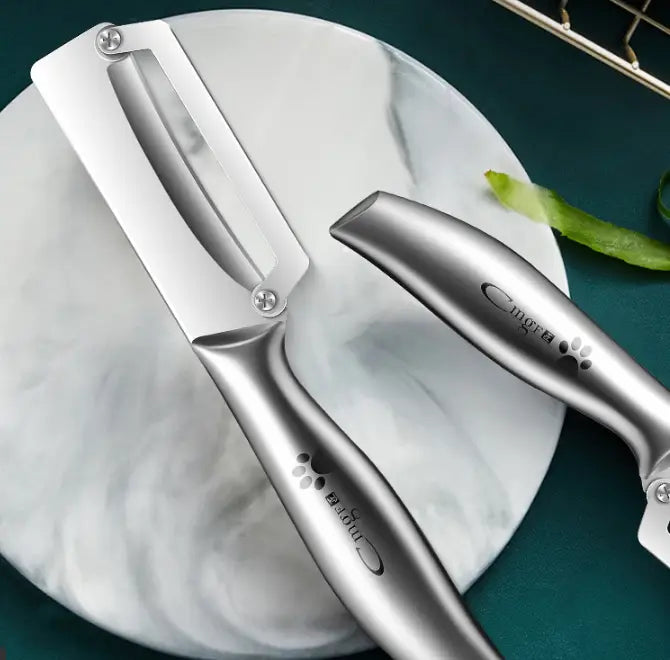 Ensemble de coupe-légumes et d’outil de coupe en acier inoxydable argenté, avec logo de marque gravé et motif d’empreinte de patte, présenté sur le coupe-légumes en acier inoxydable avec poignée en bois.