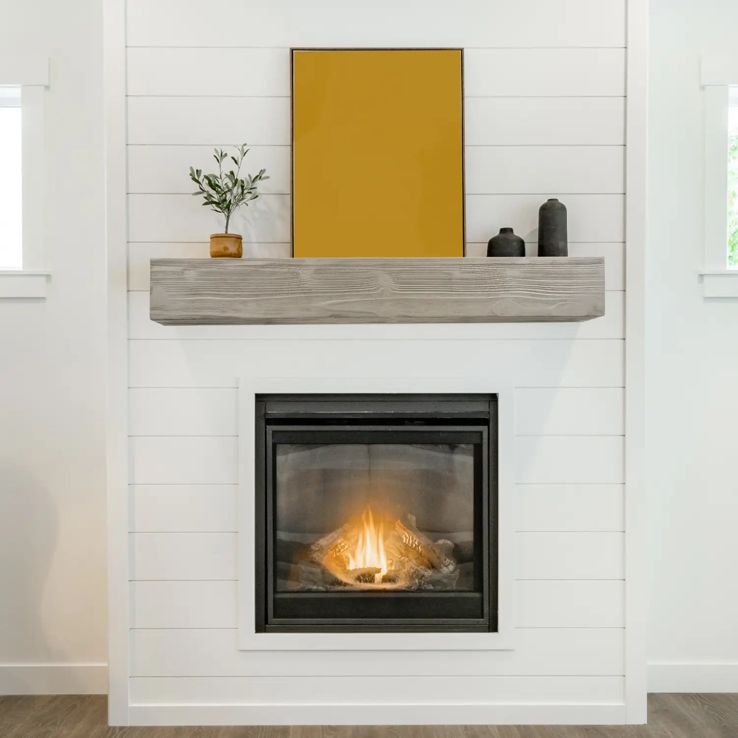Étagère de cheminée flottante en bois rustique de 72 pouces, avec une finition en bois gris et un rendu de grain subtil, placée au-dessus d’une cheminée à encadrement noir.