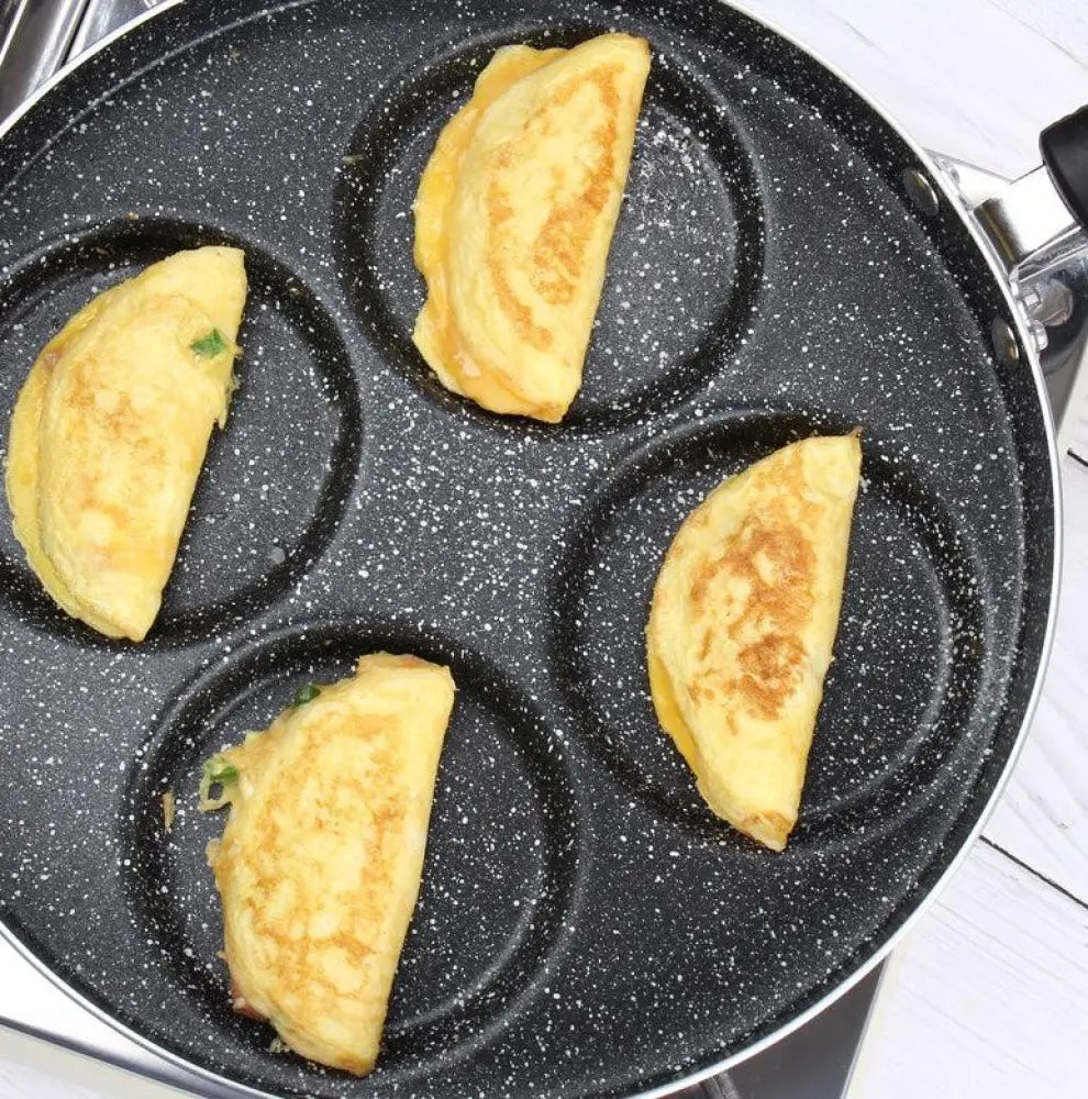 Black speckled nonstick four-egg pancake maker with golden brown omelets in each compartment for breakfast use