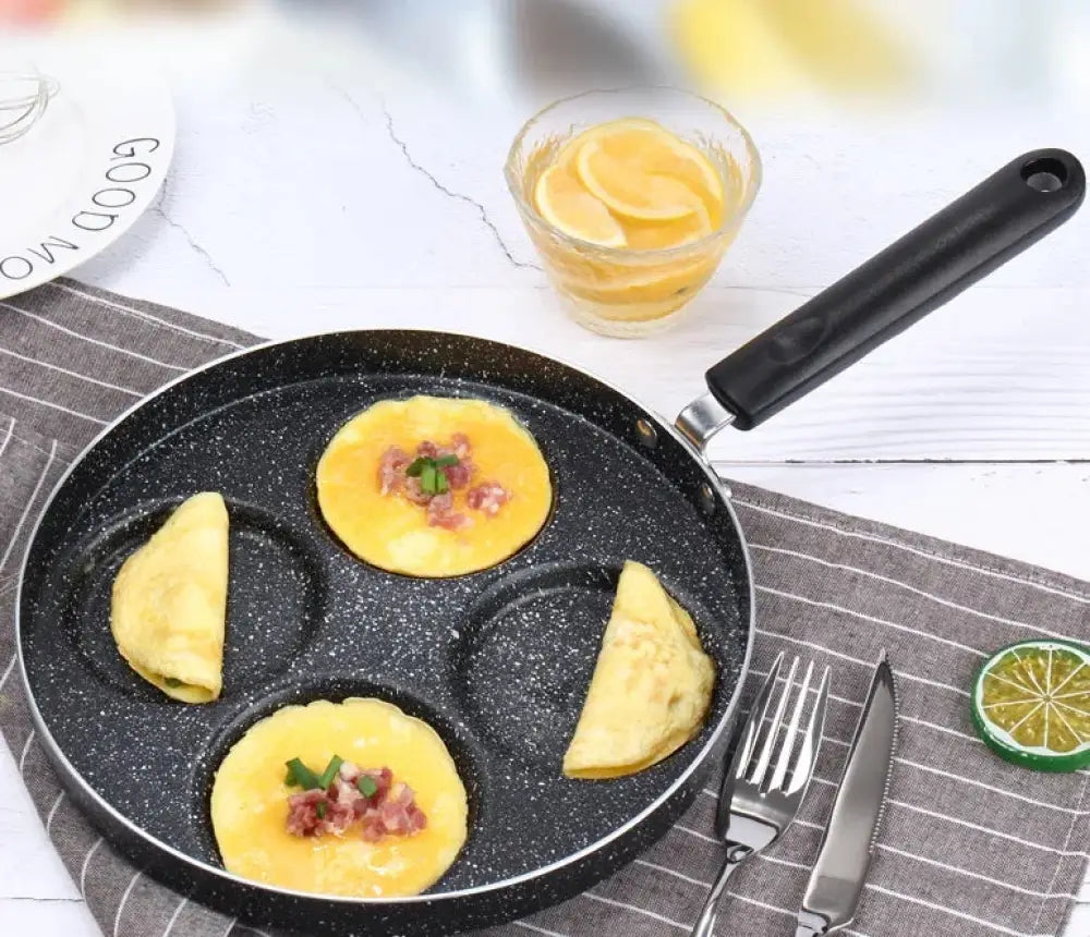 Black nonstick 4-cup breakfast pan with three circular molds cooking eggs topped with bacon and herbs