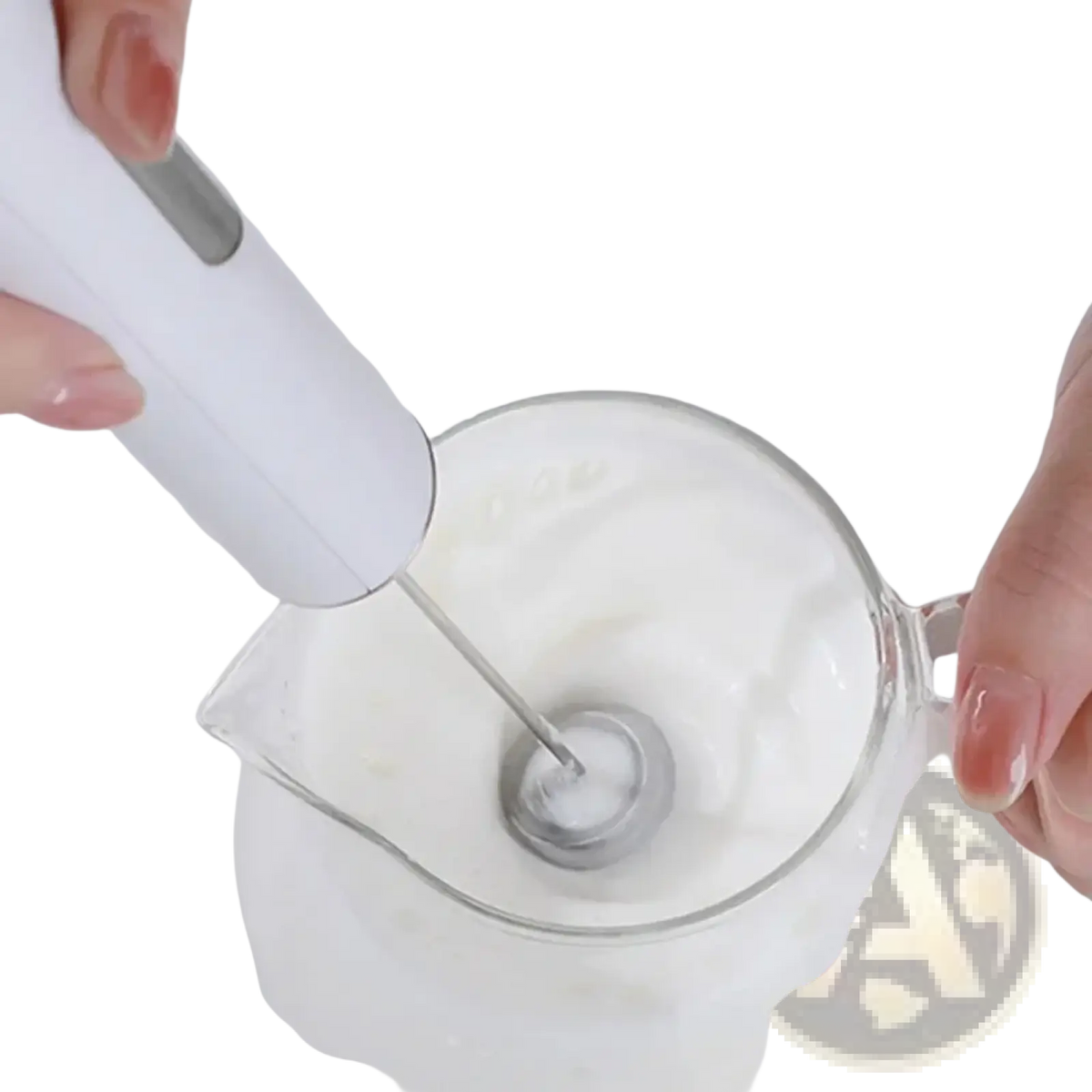 White handheld electric milk frother with silver metal whisk head whipping cream in a clear glass pitcher