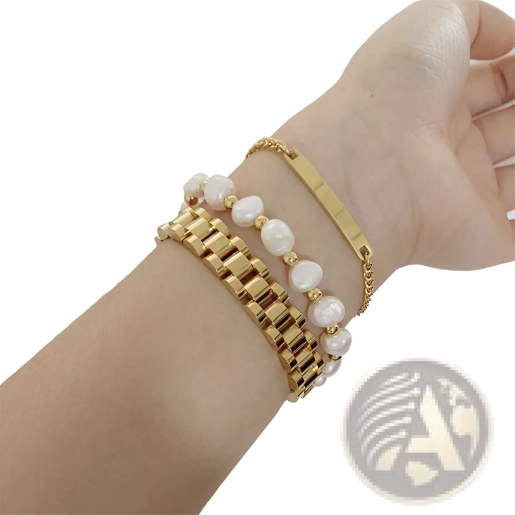 Elegant gold titanium link bracelet with pearl accents stacked with gold-toned pearl and metal bracelets on wrist