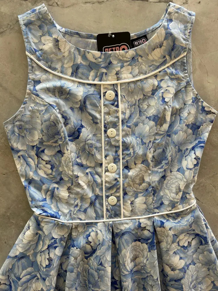 A sleeveless blue and white floral print cotton dress with fitted bodice button-front closure and pleated skirt