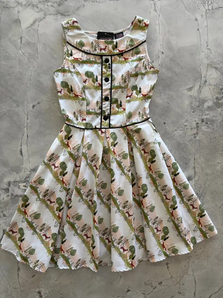 Sleeveless white Elizabeth dress in woodland sunset cotton print with deer and trees, black trim on neckline and waistband