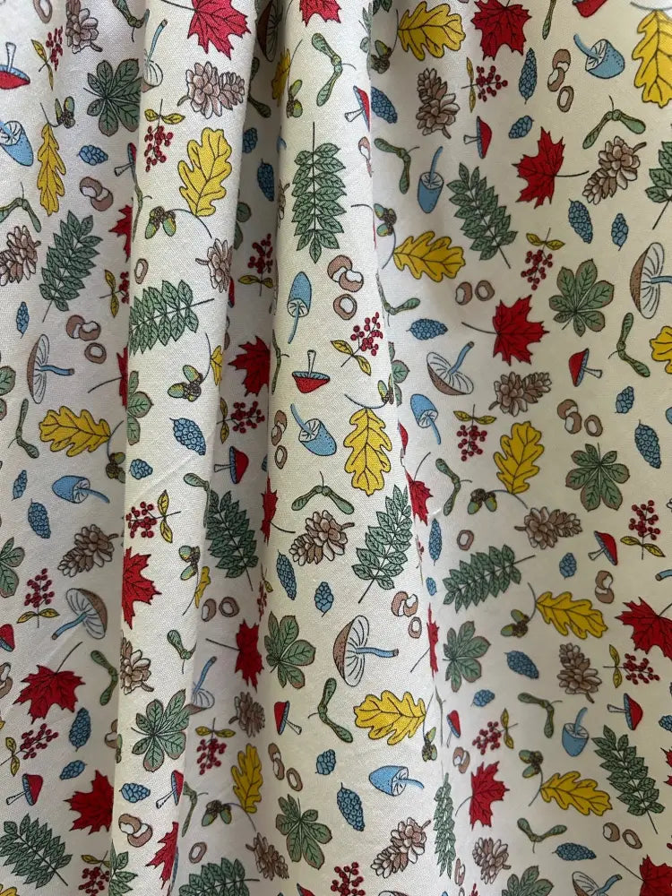 A cream-colored vintage cotton floral dress with pockets featuring autumn leaves pinecones mushrooms and berries pattern