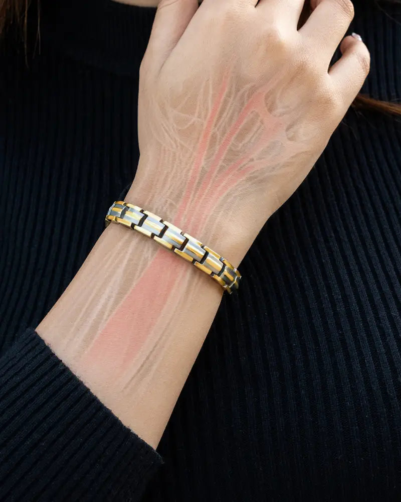 A sleek two-tone gold and silver titanium magnetic bracelet with segmented interlocking design worn on a wrist
